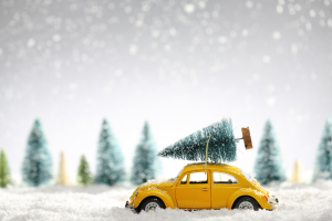 Miniature yellow car with fir tree on snow