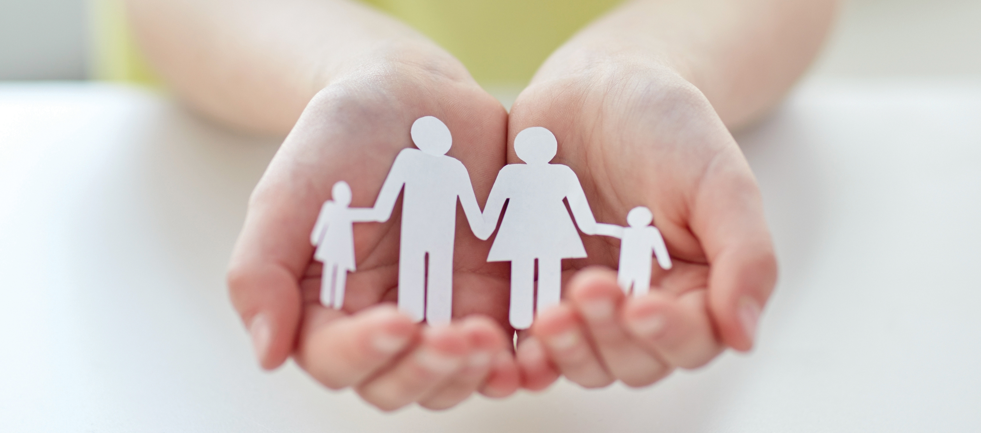 people, charity and care concept - close up of child hands holding paper family cutout at home